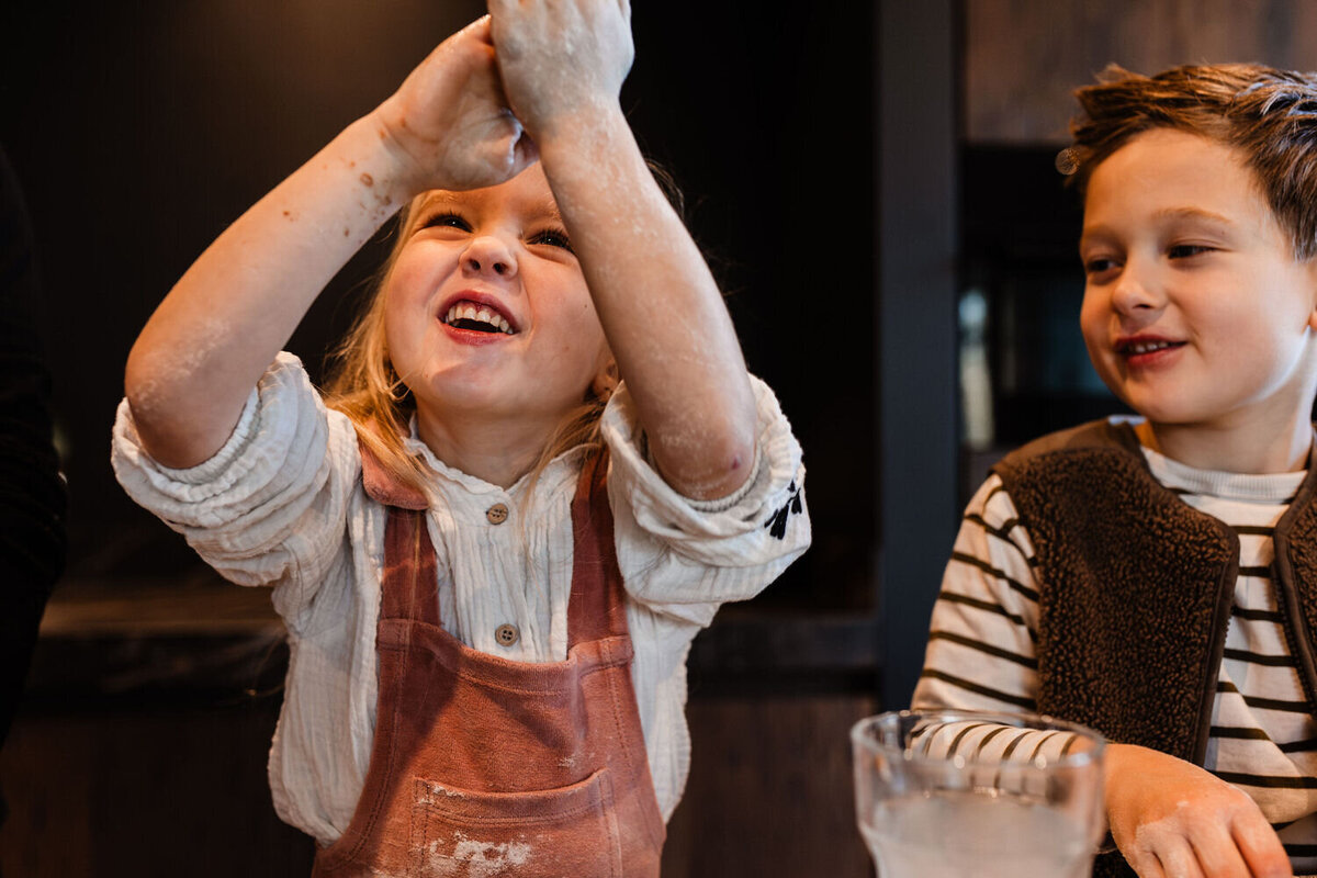 meisje draait met veel plezier en lachen balletjes van deeg en broertje kijkt toe