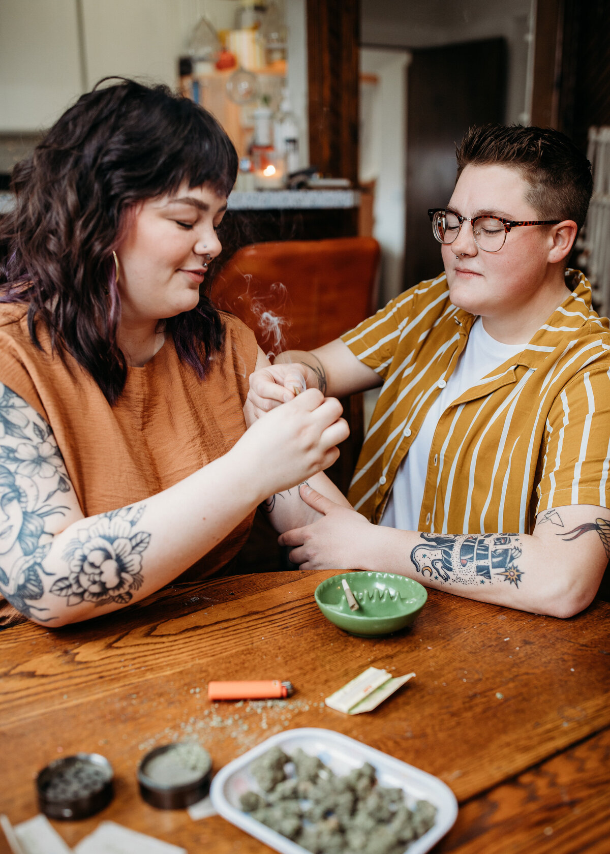 A couple at a wooden table rolling a joint.