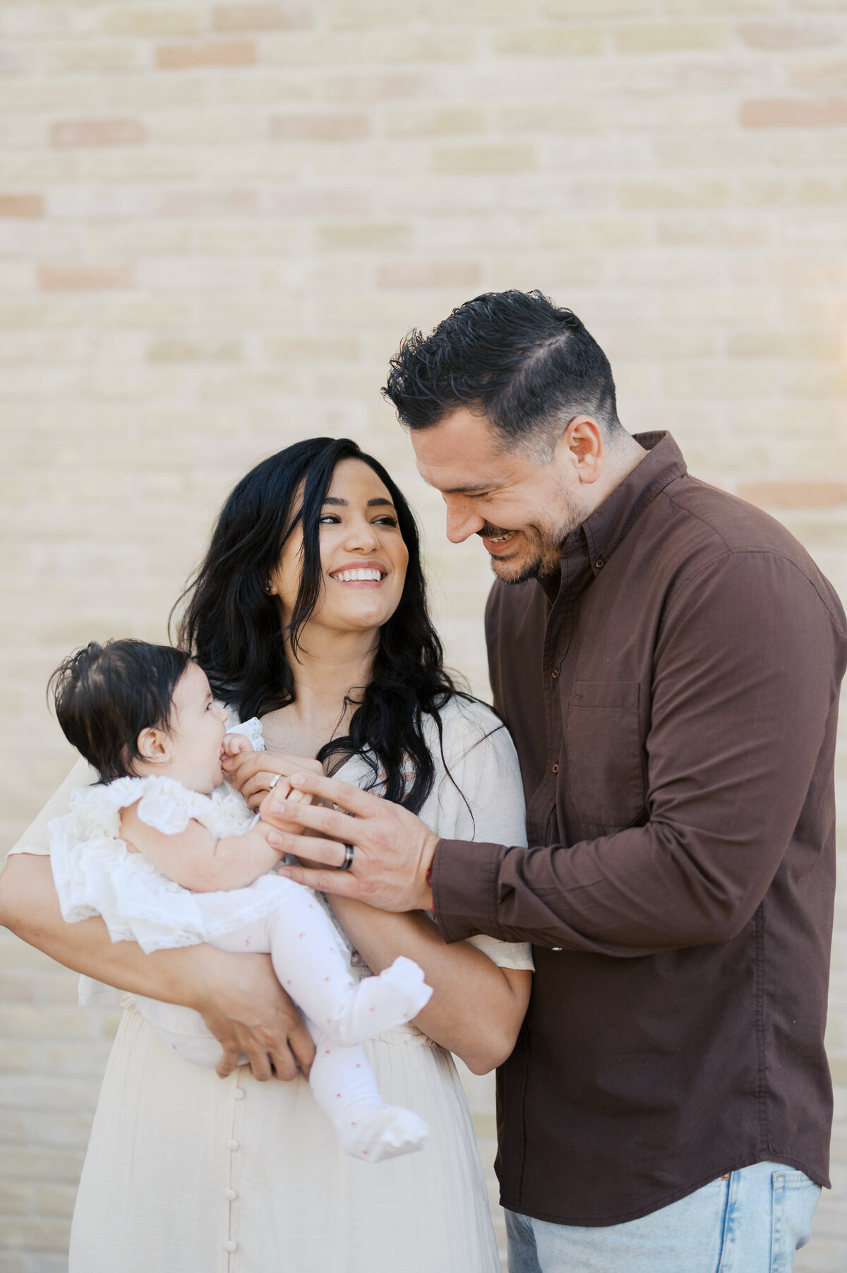 parents smile while holding baby girl outside