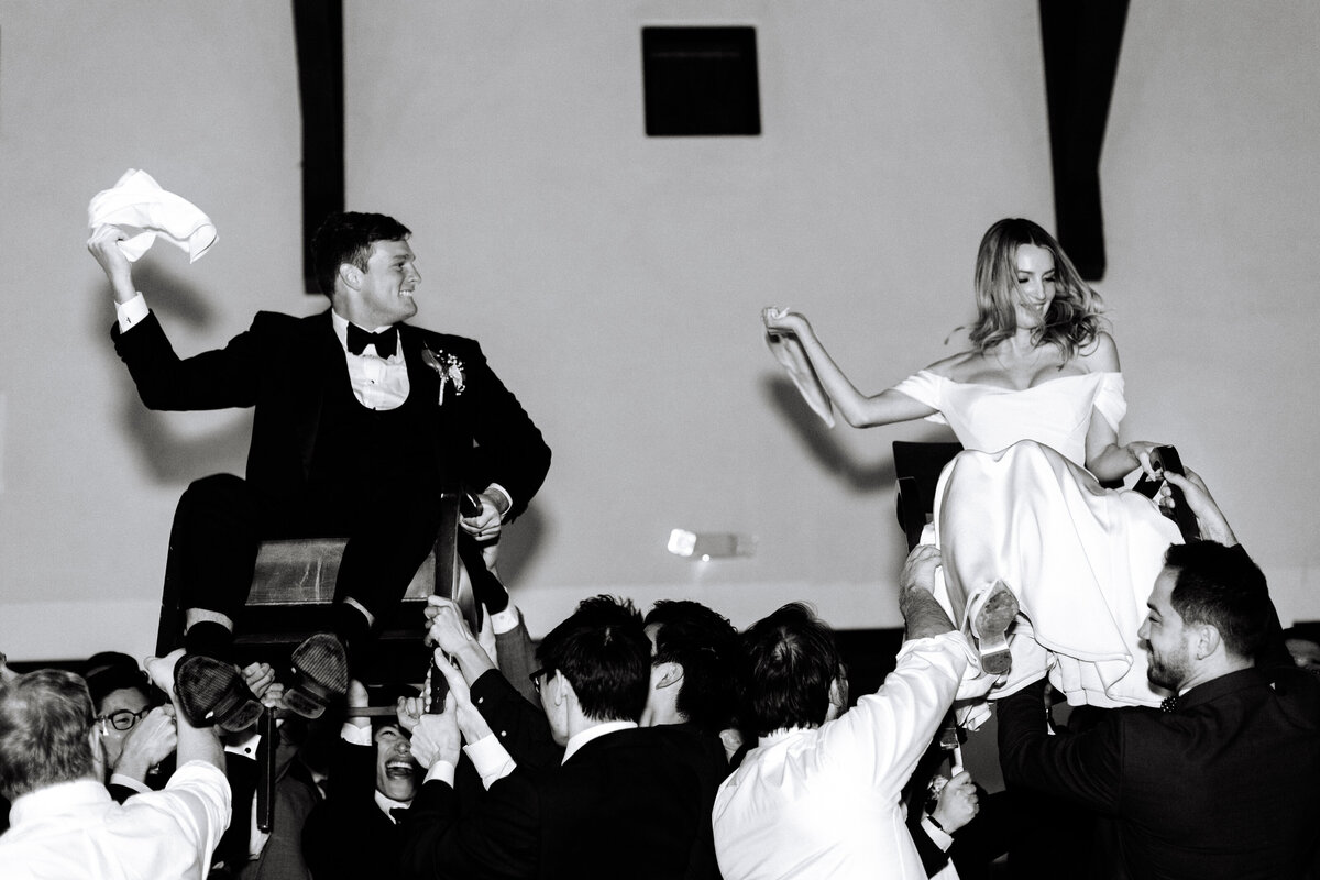 black and white image of bride and groom being lifted high in chairs while dancing at sonoma wedding reception.