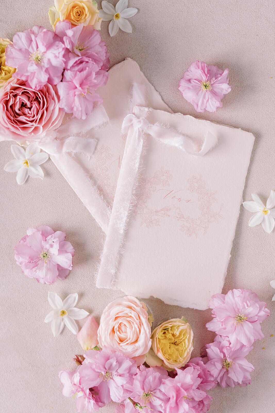 flat-lay of pink wedding day stationery vow books displayed with pink flowers for a luxury westacott wedding at blenheim palace