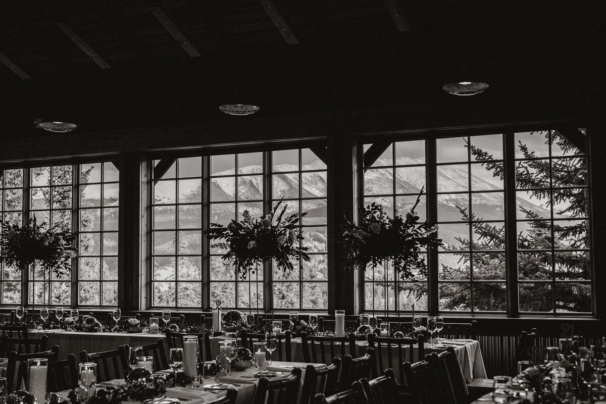 Black and white image of reception tables with towering floral decor and mountain views in Breckenridge.