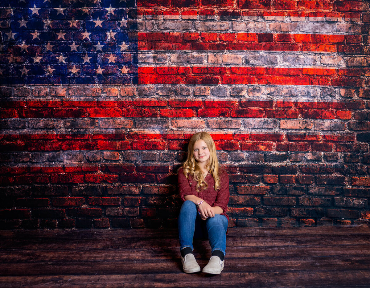 Teen poses against American flag wall in Prescott kids photos by Melissa Byrne