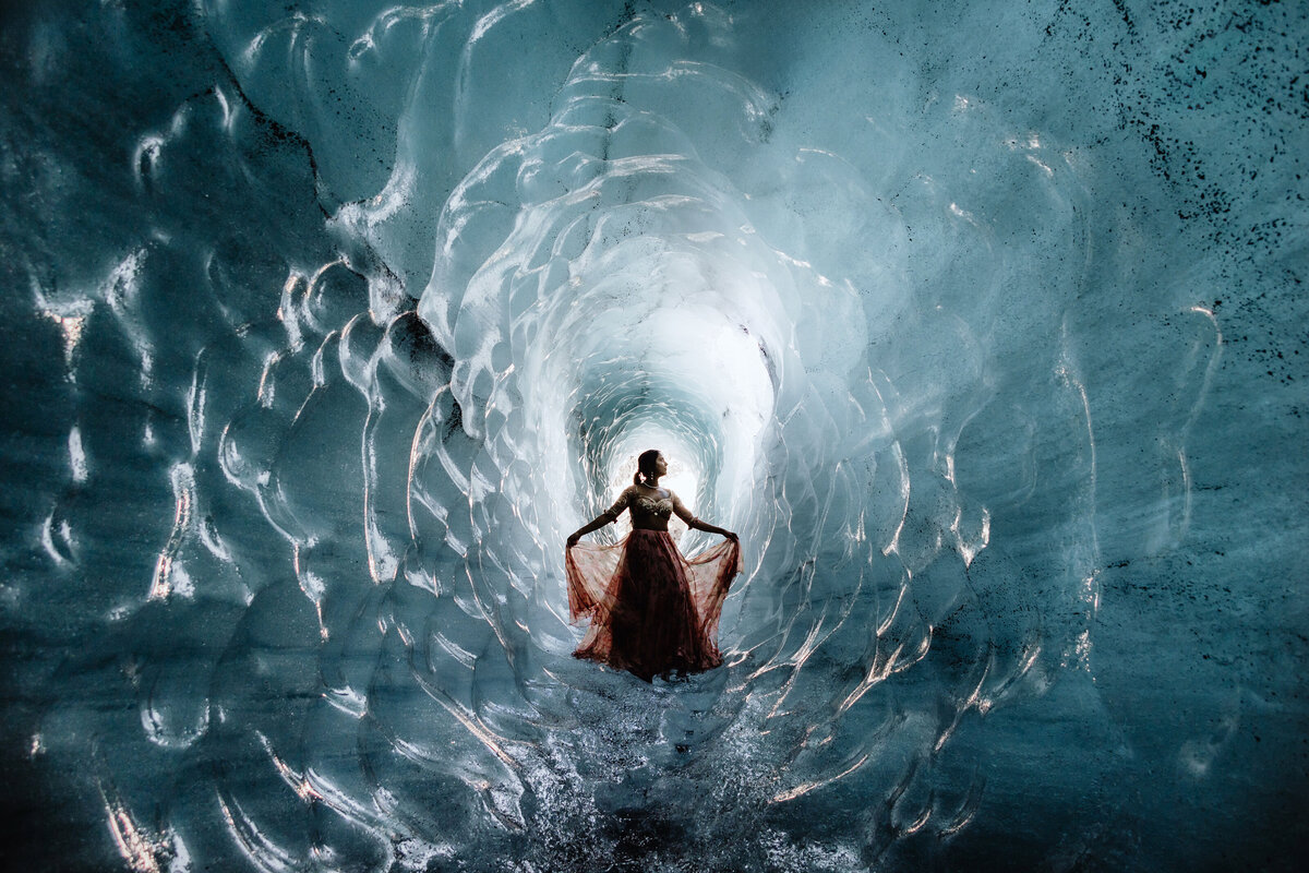indian bride is posing in a blue ice cave on her wedding day in Iceland
