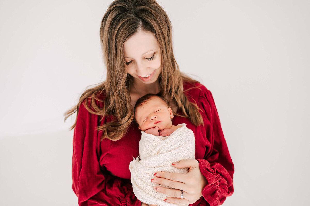 mom looking down at sleeping newborn  in photography studio in Branson