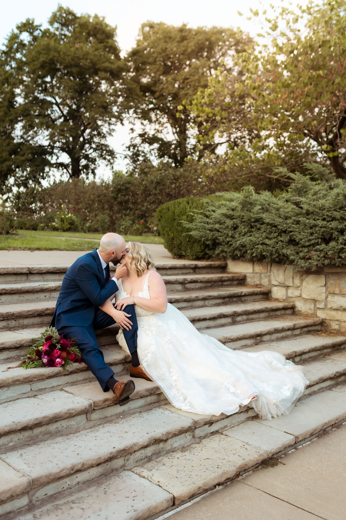 Bride and groom having a romantic moment kissing on stairs inside rose garden in Kansas City Missouri.