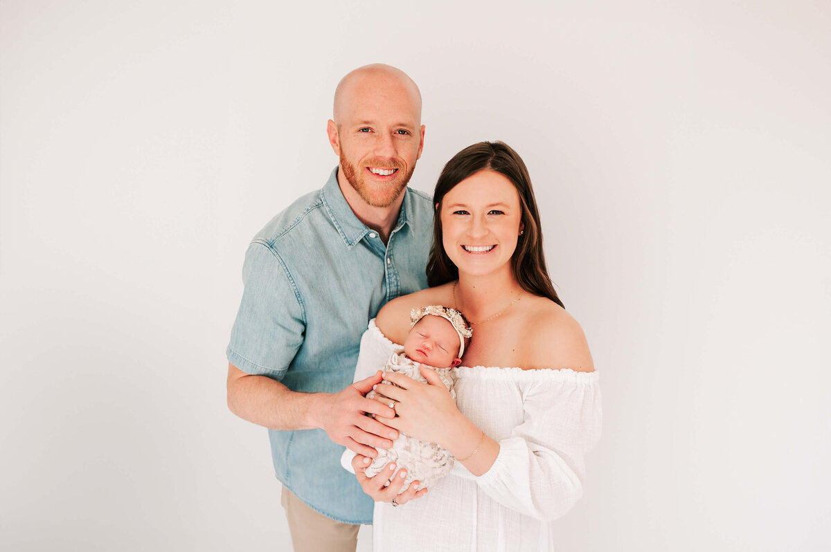 parents smiling holding baby girl in Springfield MO newborn photography studio