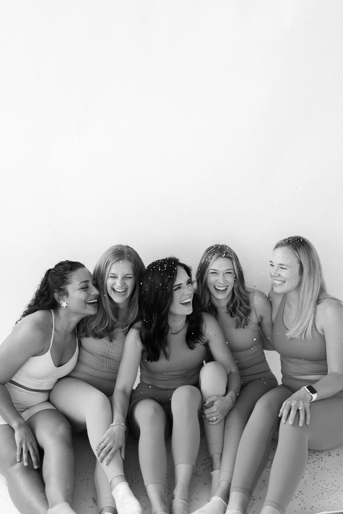 Women smiling and hugging while sitting on the floor