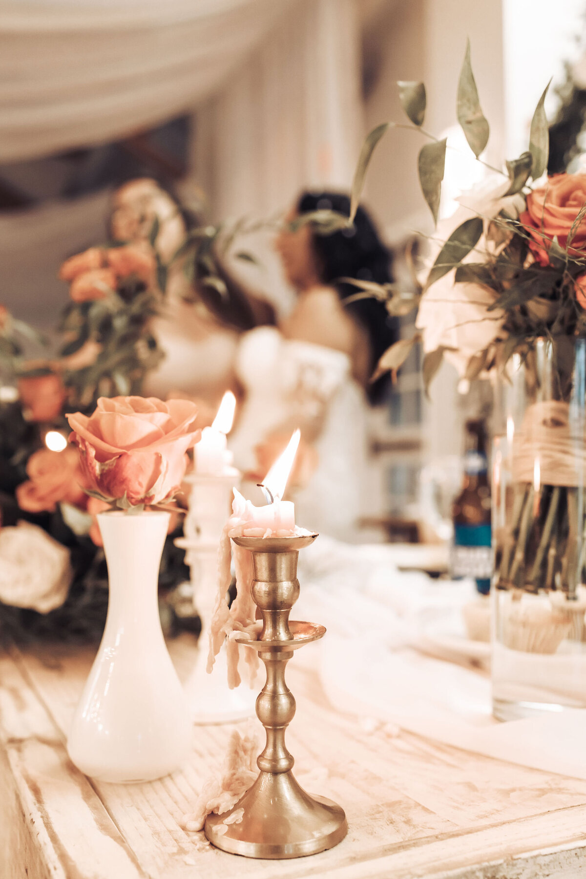 close up of orange roses in vases and gold candlesticks