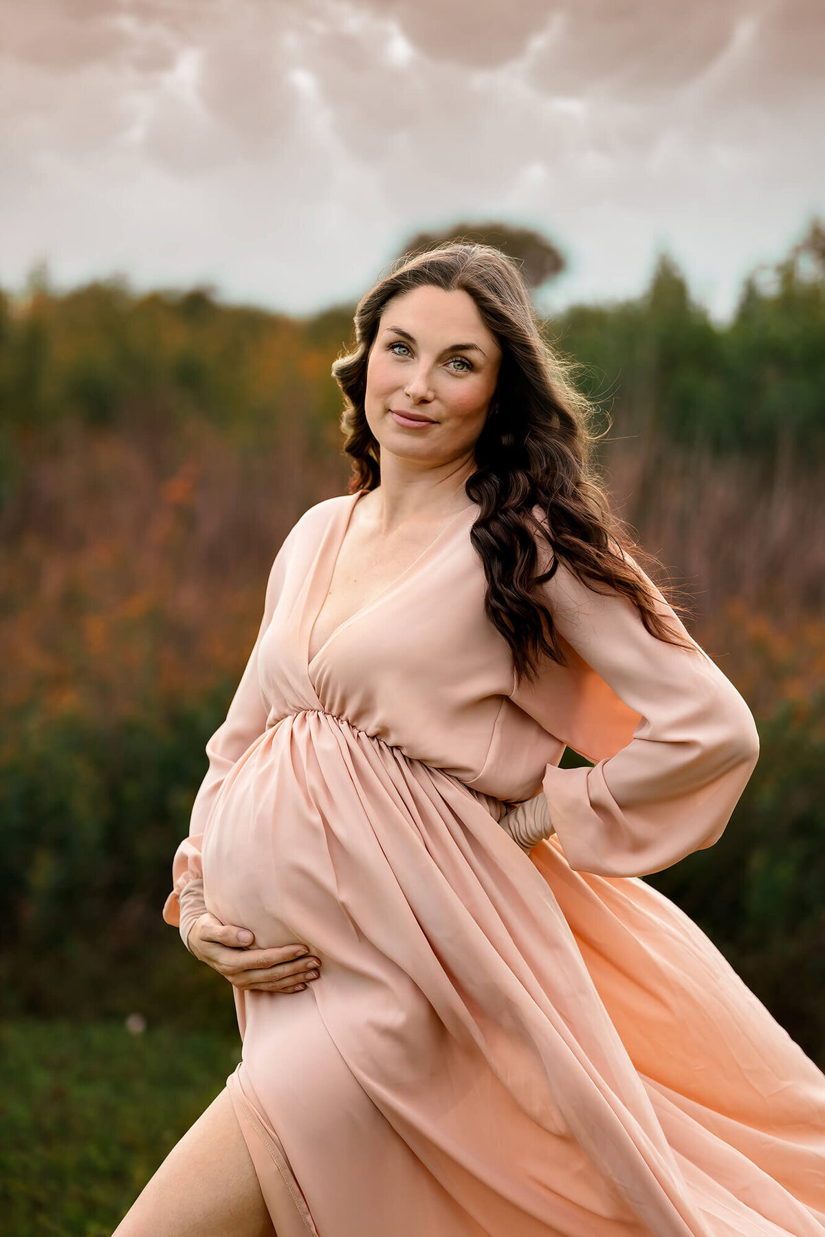 Golden hour maternity photography model wearing light pink dress.