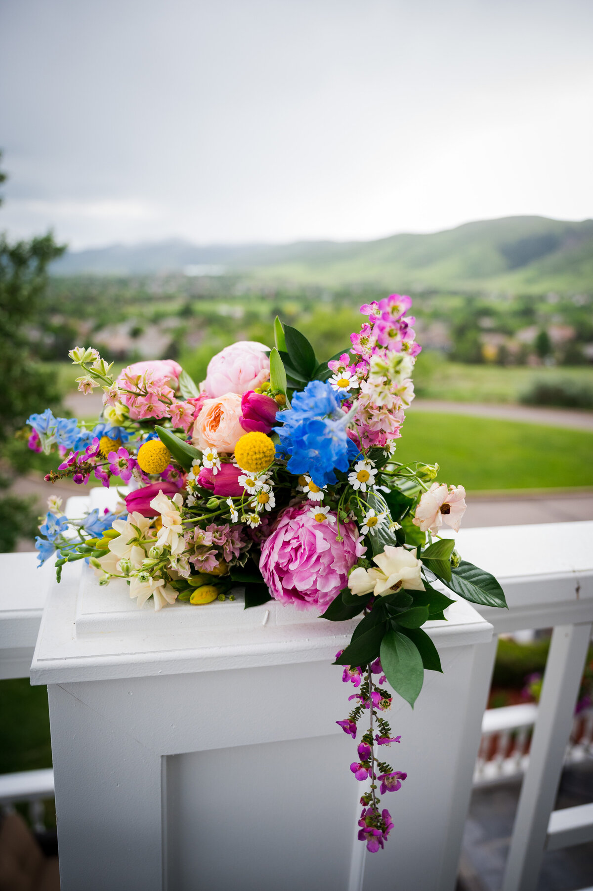 A wedding bouquet sits on a balcony with a Colorado landscape in the background.