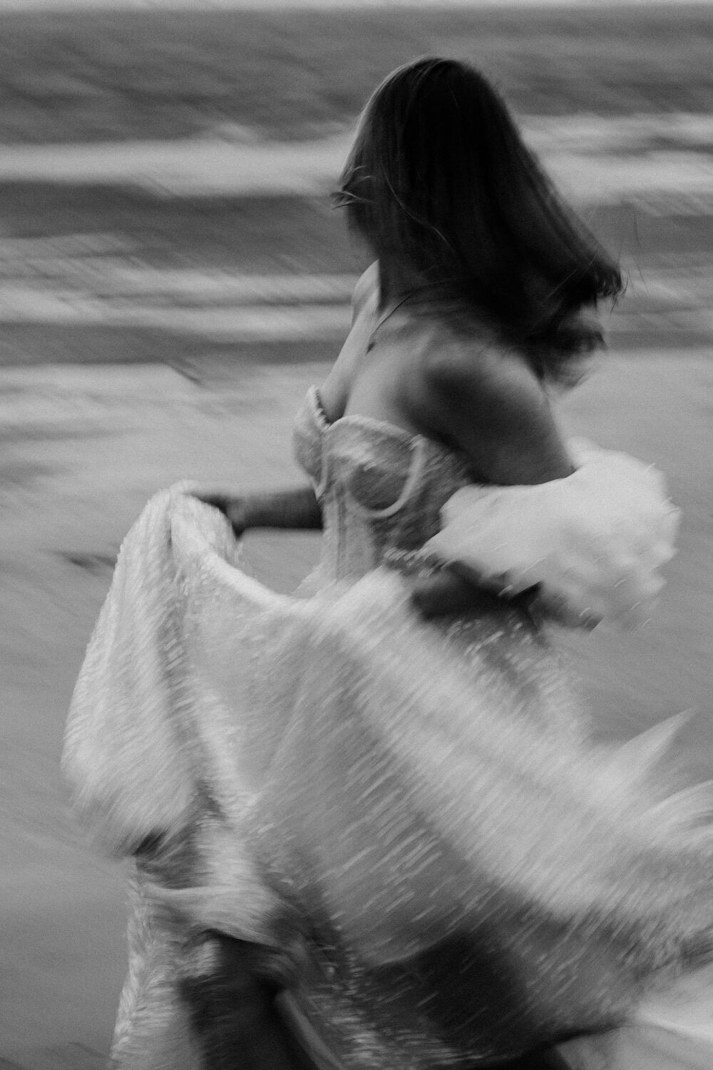 Bride running on the seashore while holding her gown
