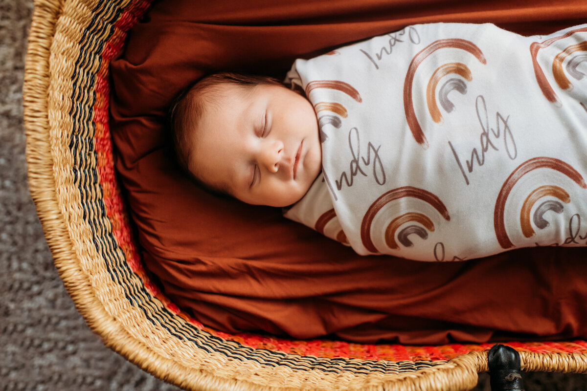 Newborn Photographer, Baby in a blanket snuggled in a Moses basket.