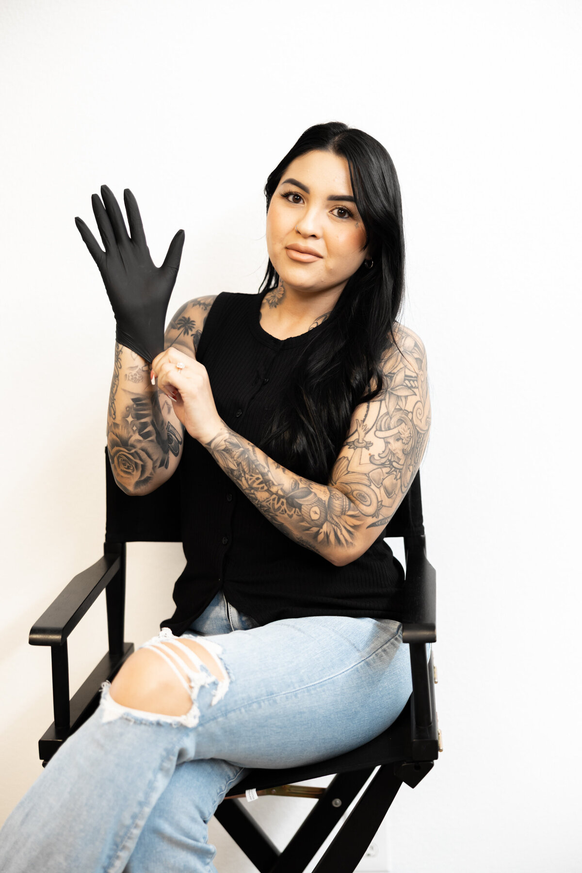 Tattooed hairstylist in black gloves smiling during a branding photography session. Photograph by Yucaipa branding photographer Kaitlyn Dawn Photography.