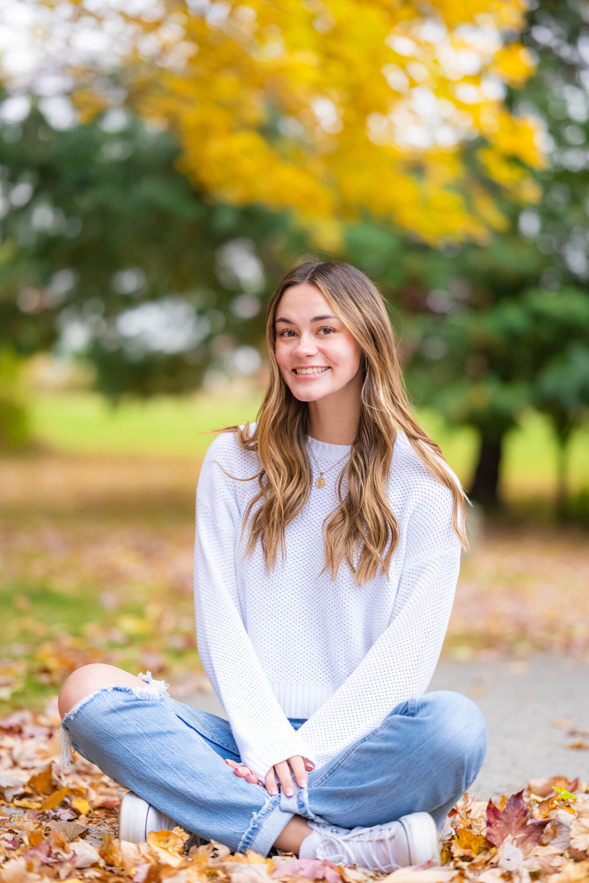 high school senior girl sitting on leaves