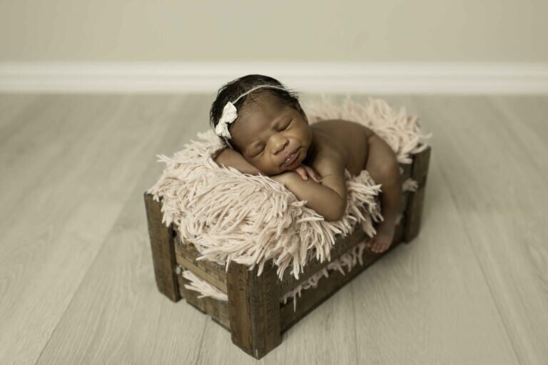 Newborn baby girl peacefully sleeping inside a rustic ruler box, symbolizing growth and new beginnings, creating a unique and charming portrait