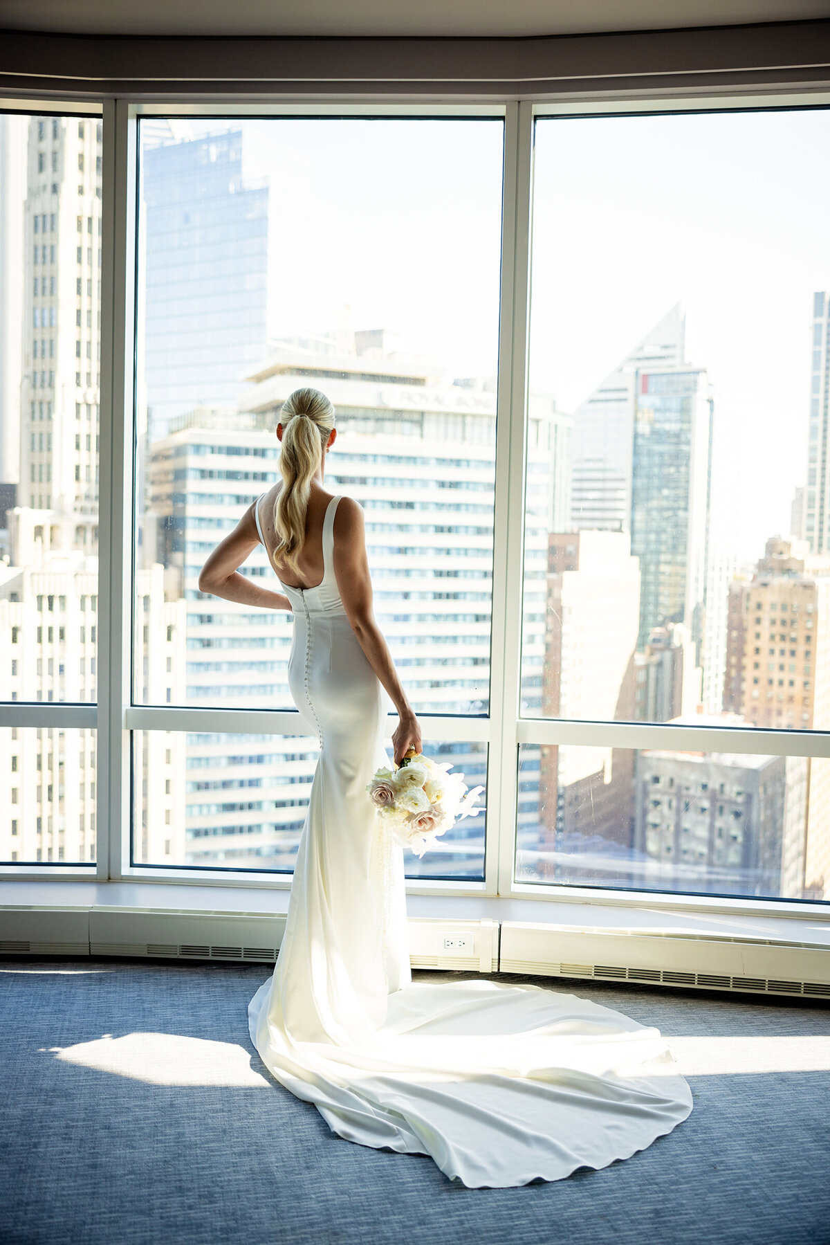 Tall fir bride looking out to Chicago skyscrapers from floor to ceiling window at Trump hotel suit