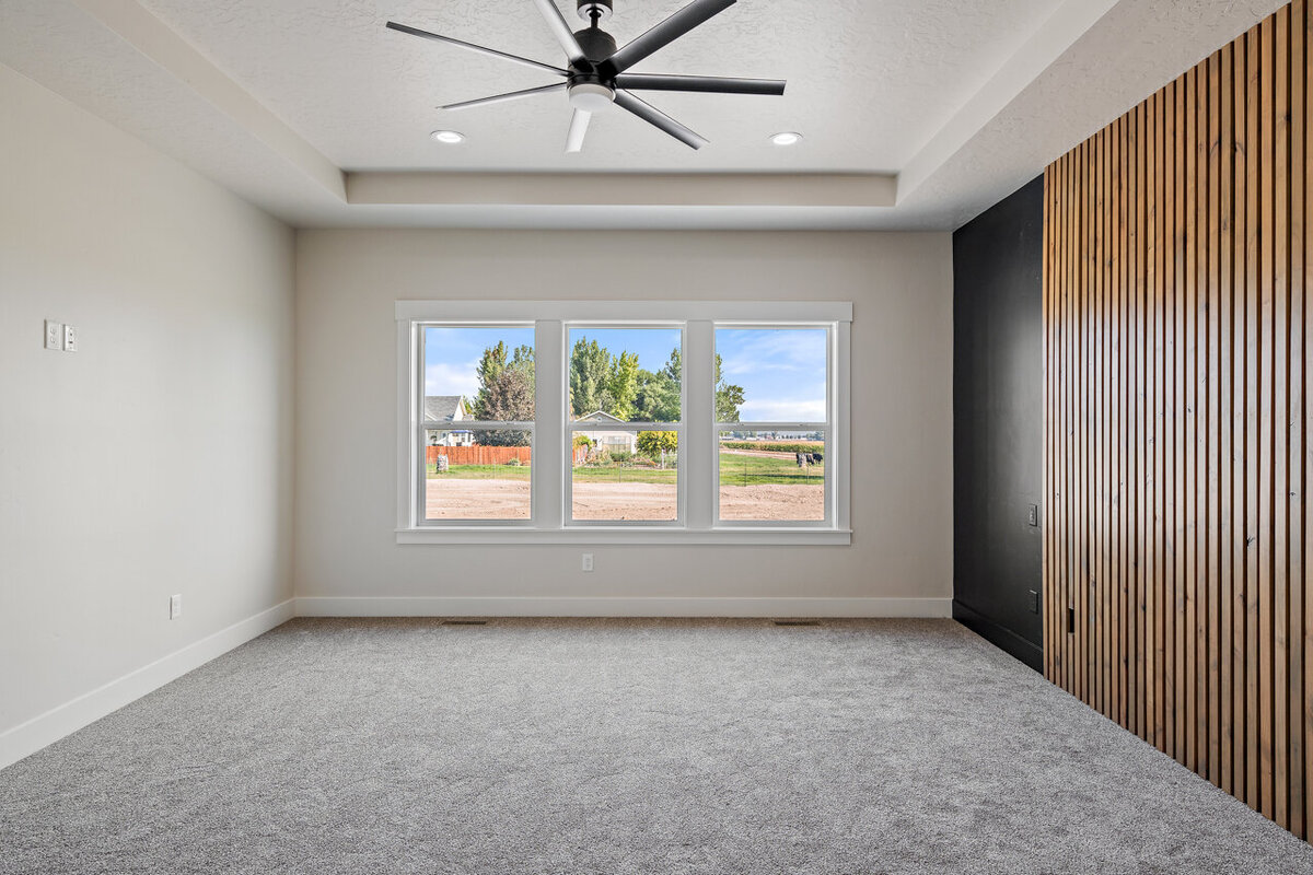 living room space with light carpet painted black and wooden accent wall and black ceiling fan