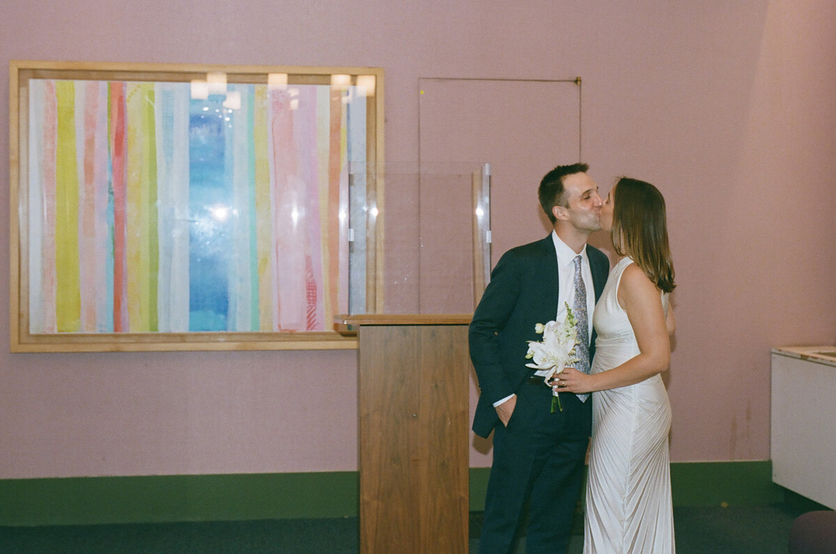 A wedding couple kissing in a small room.