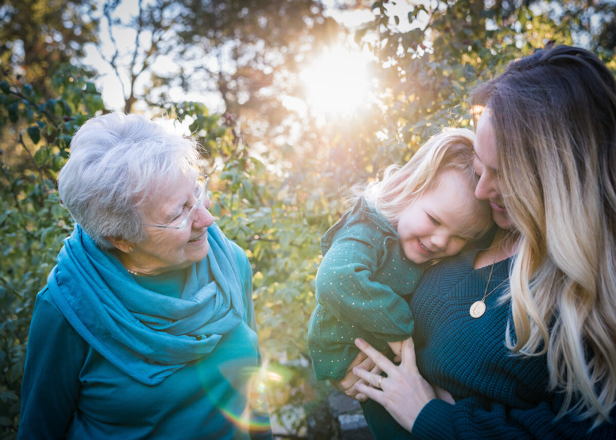 Three generations laugh together with sun burst
