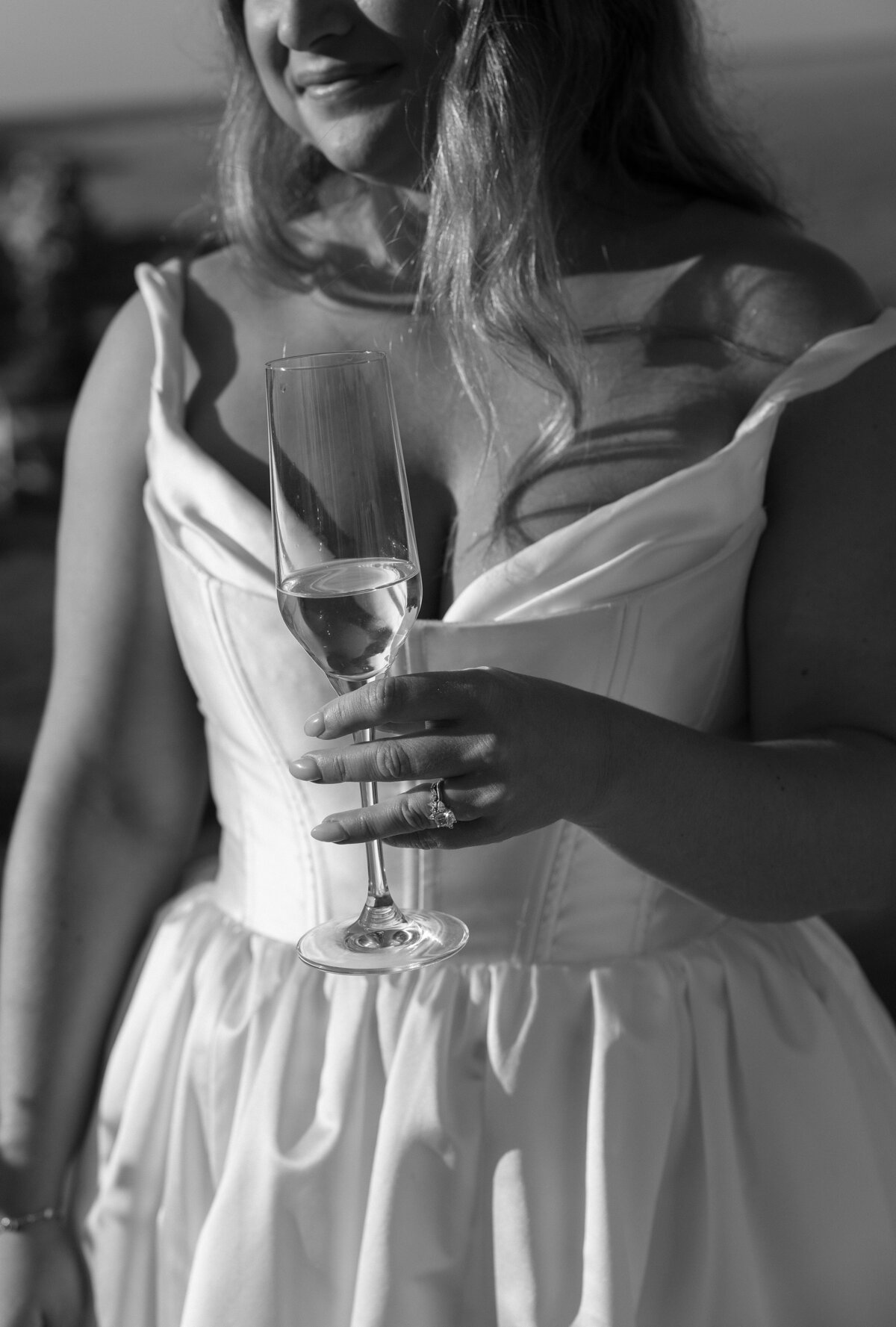 Bride holds class of champagne in her wedding dress at Cliff House Maine.