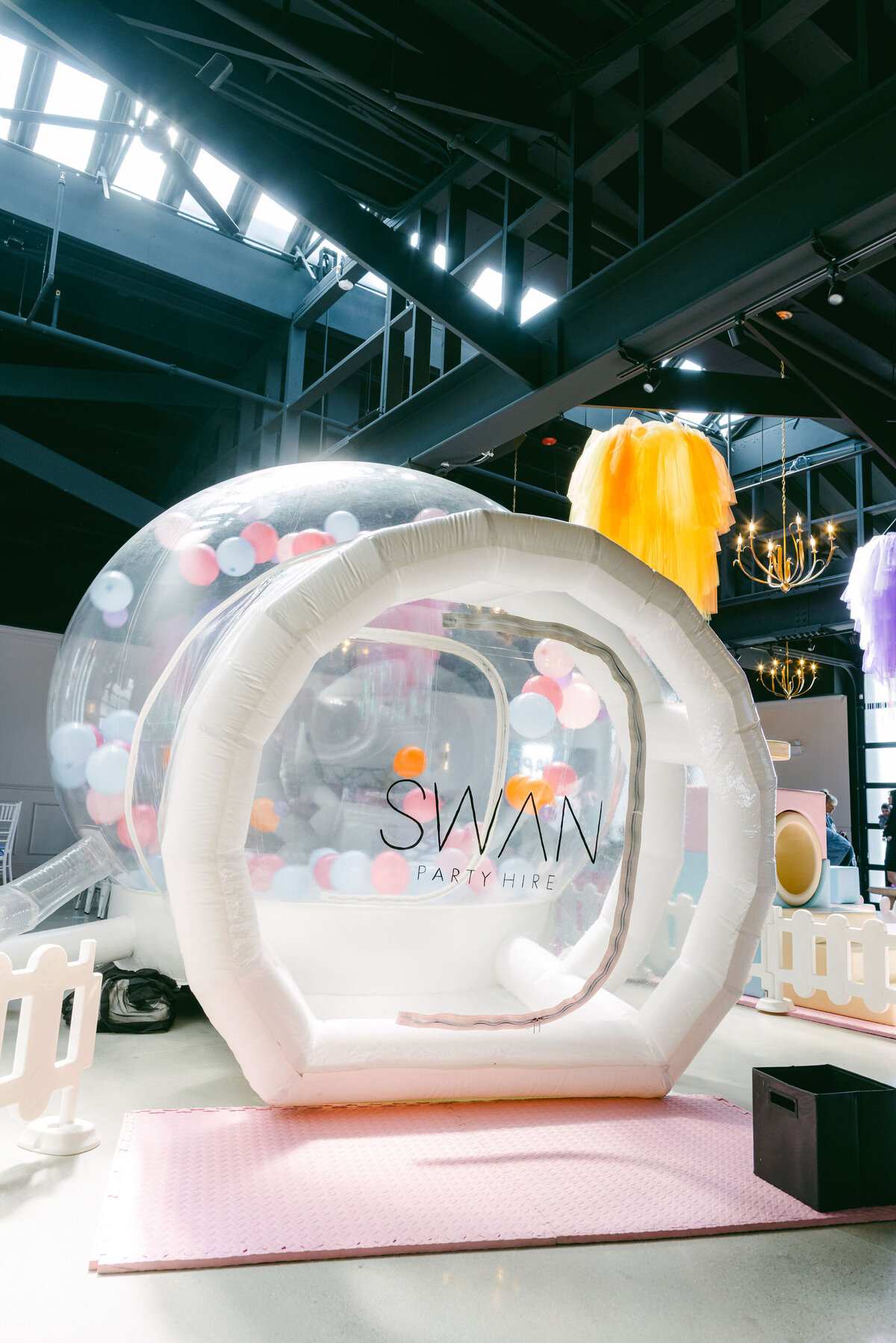 Colorful bounce house at a children’s birthday party venue, surrounded by vibrant balloons, playful decorations, and festive table settings, creating a fun and lively atmosphere