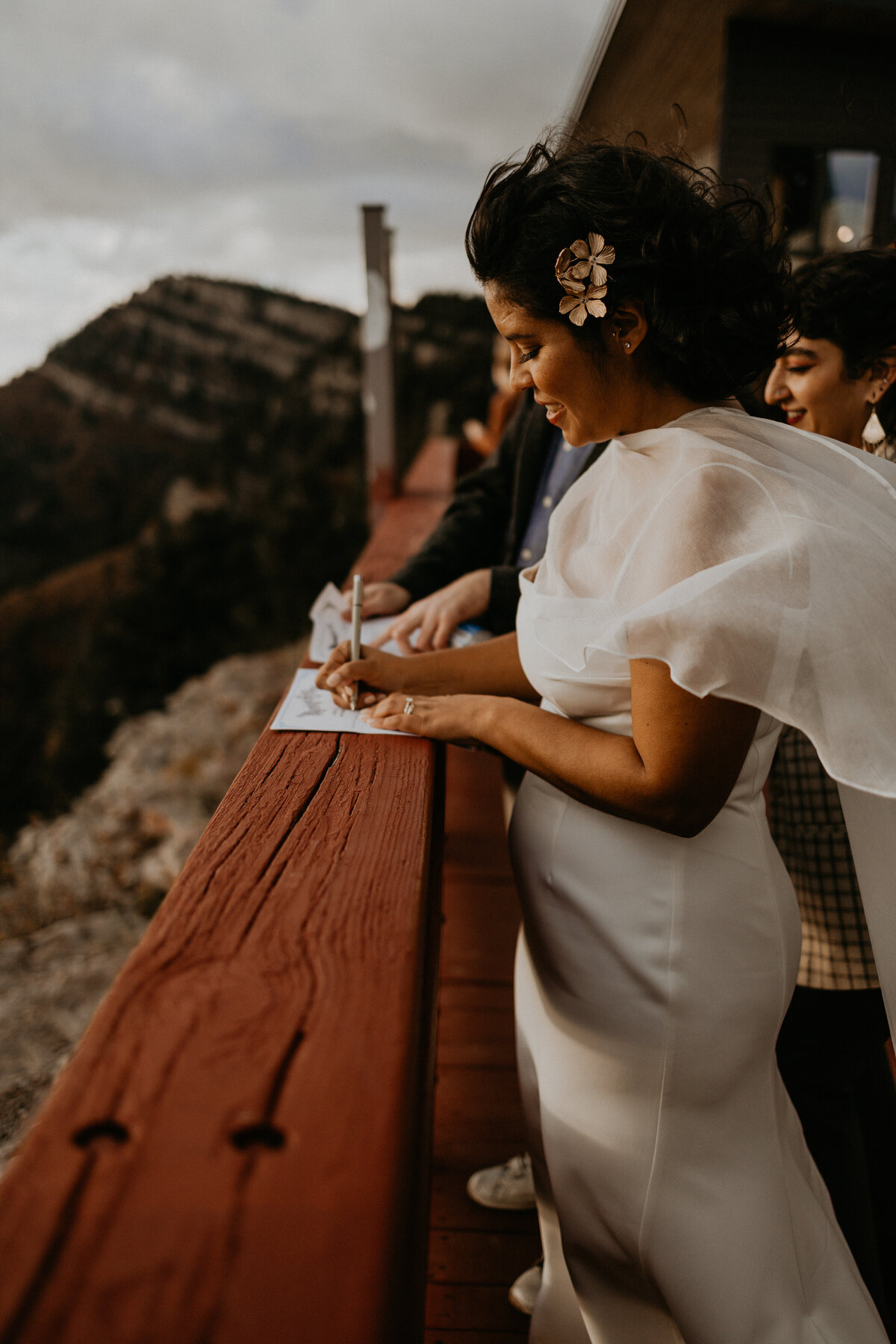 bride and groom signing paperwork on Sandia Peak Tramway boardwalk overlooking Albuquerque