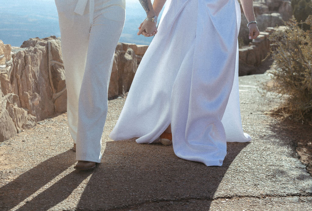 The feet of a newlywed couple walking together.