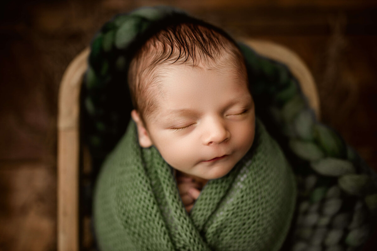 sleeping infant swaddled in green