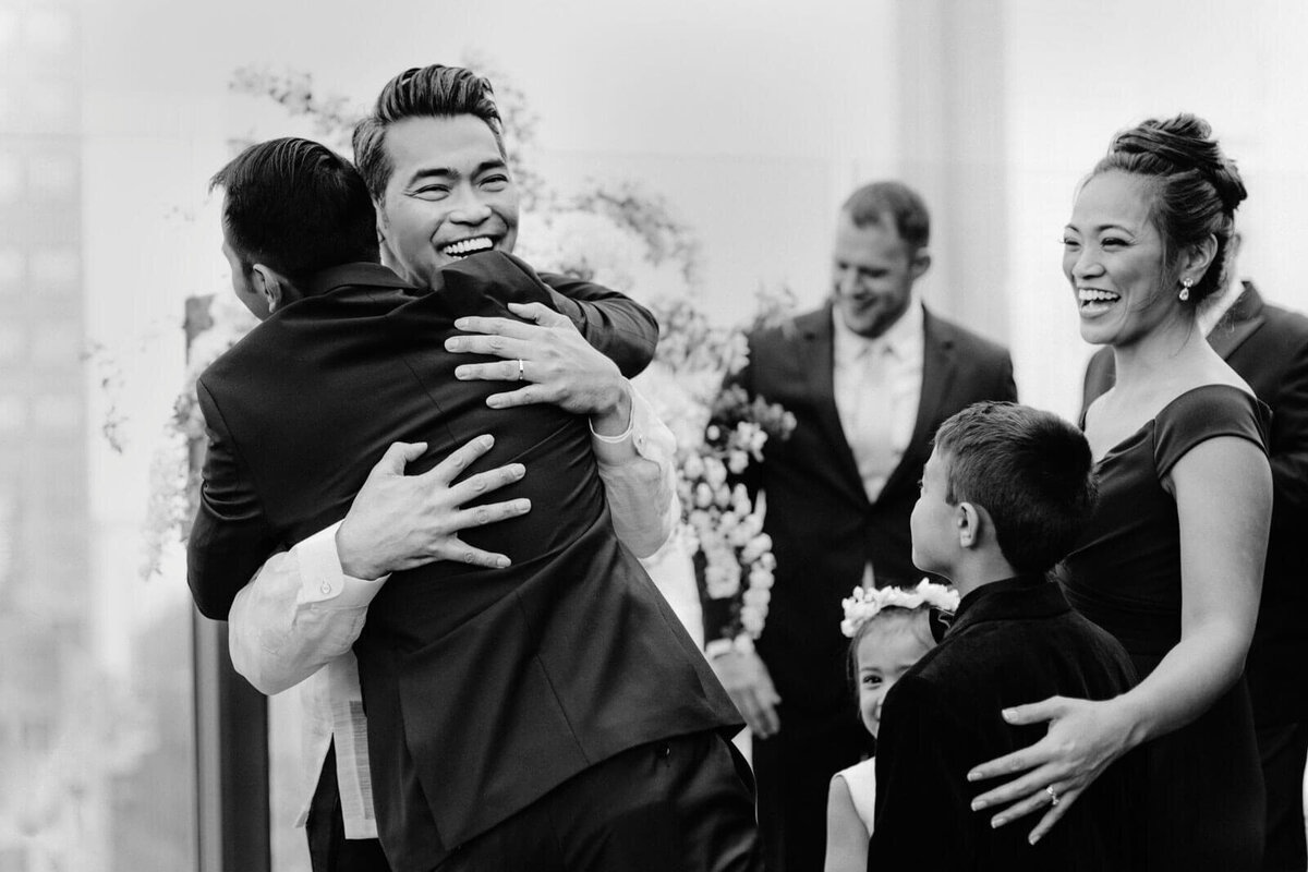 The groom is hugging a man after the wedding ceremony in The Skylark, New York. Wedding Image by Jenny Fu Studio