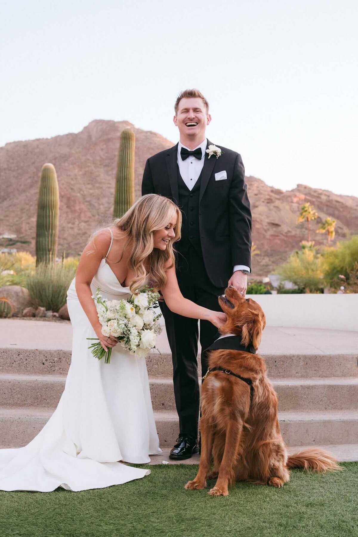 Bride and groom with their dog during a Mountain Shadows wedding in Scottsdale, Arizona, smiling against the desert mountain backdrop.