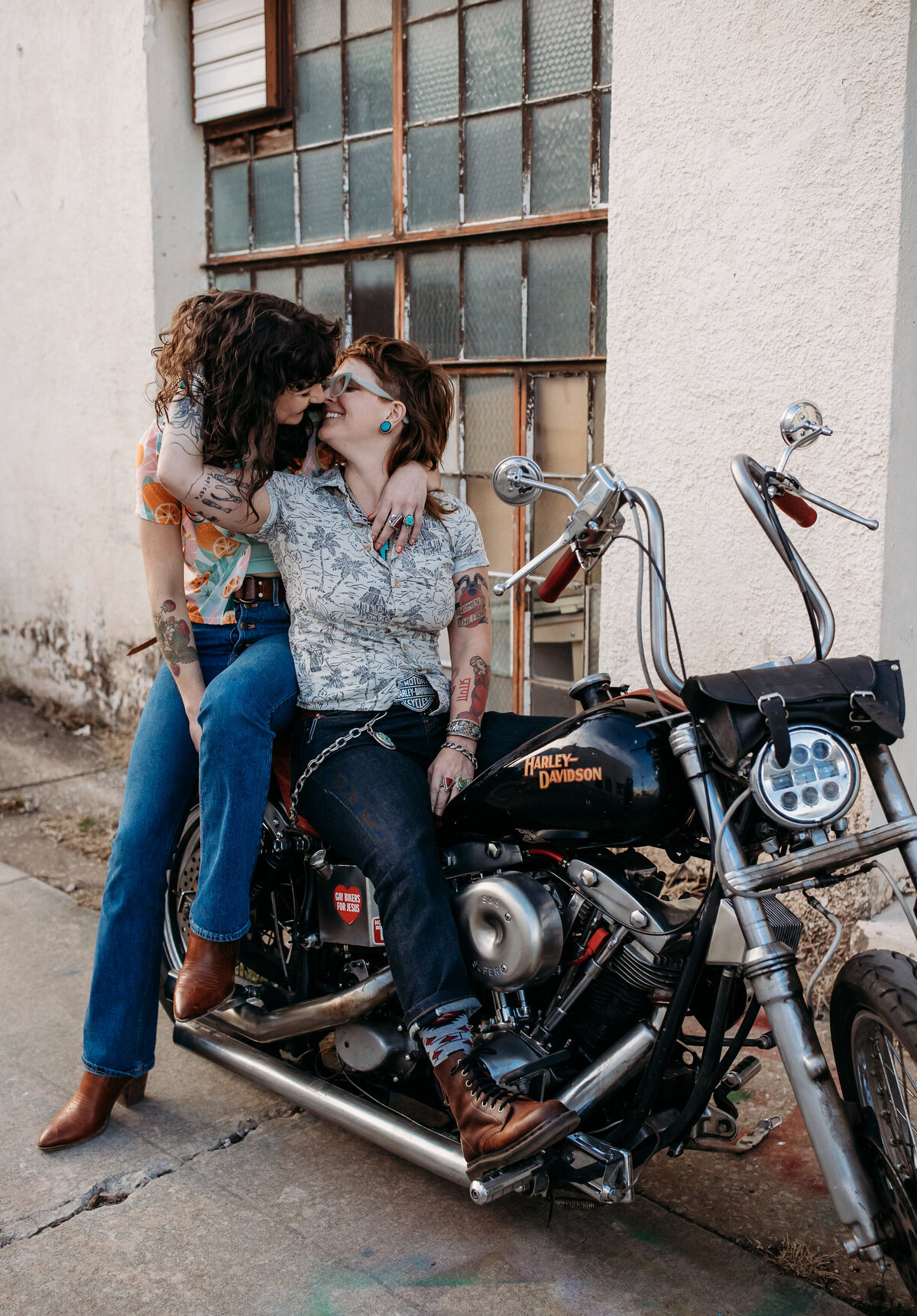 A couple seated on a motorcycle, sharing a kiss
