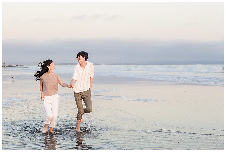 engaged couple running through ocean