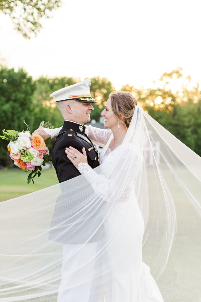groom in military uniform smiling at bride in her wedding dress