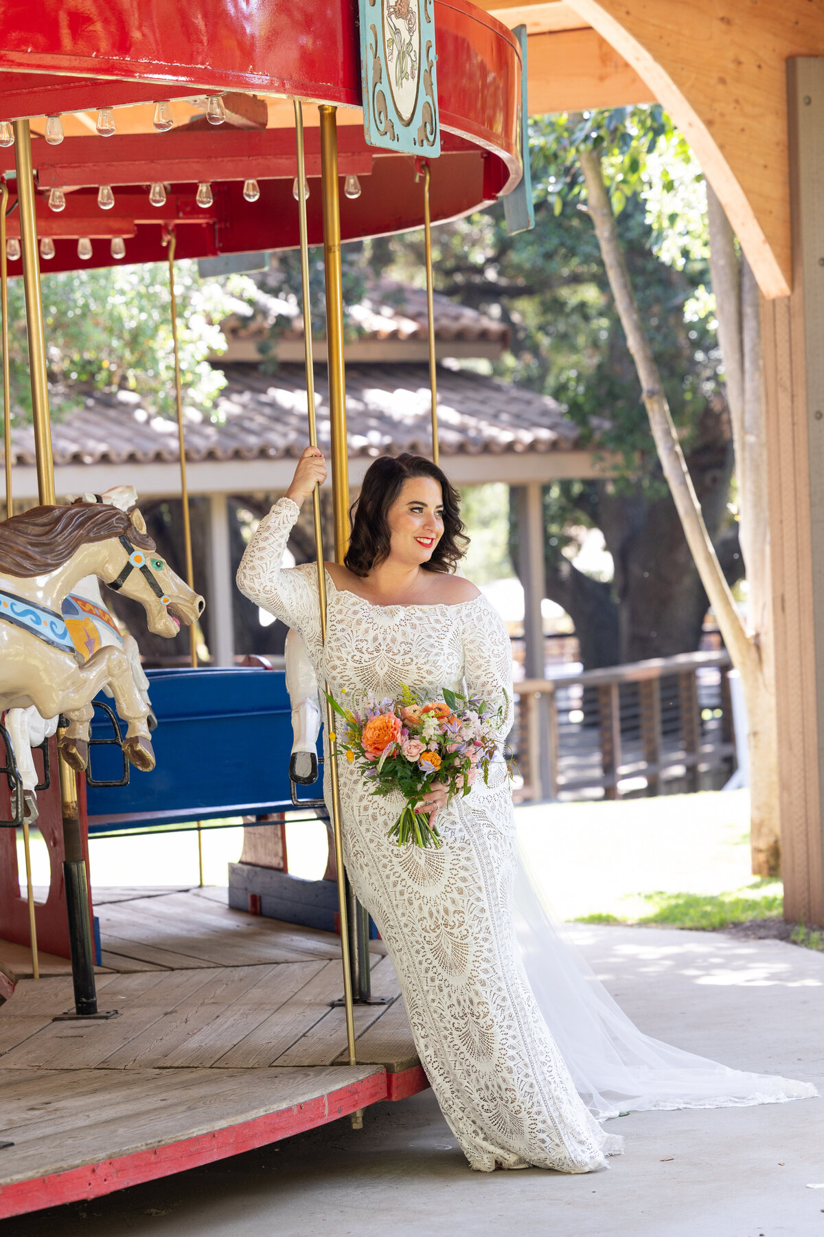 A bride leaning on the side of a merry go round