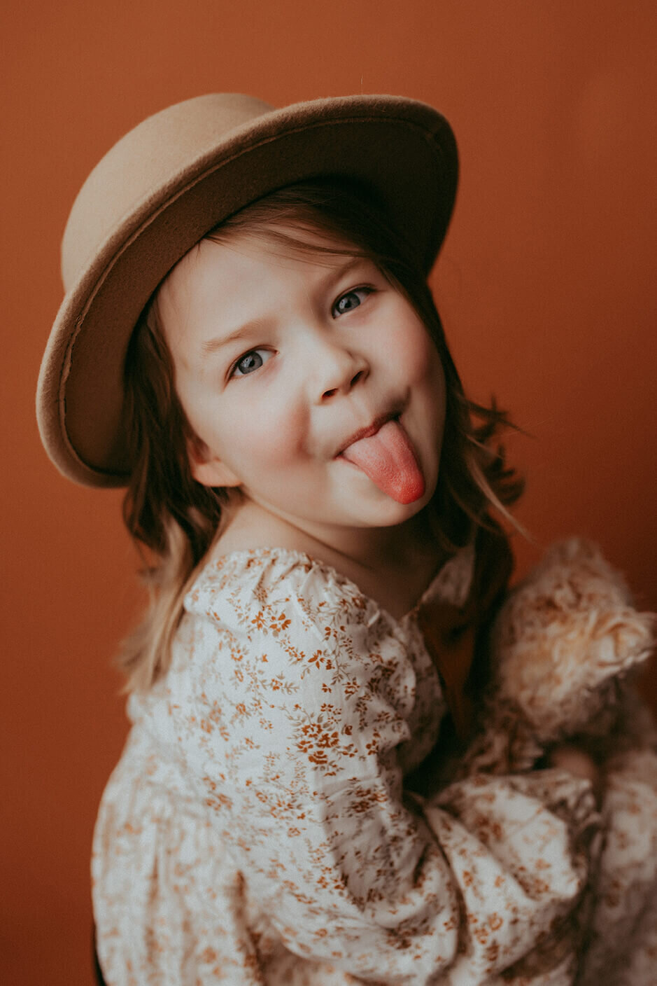 Girl sticking tongue out on brown backdrop