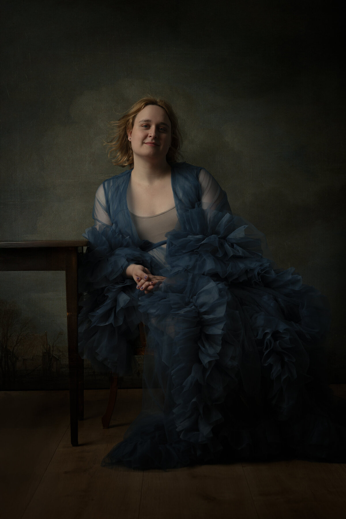Studio Ace Photography Zaltbommel schilderachtig portret van transgender dame in blauwe tule jas zittend aan tafel