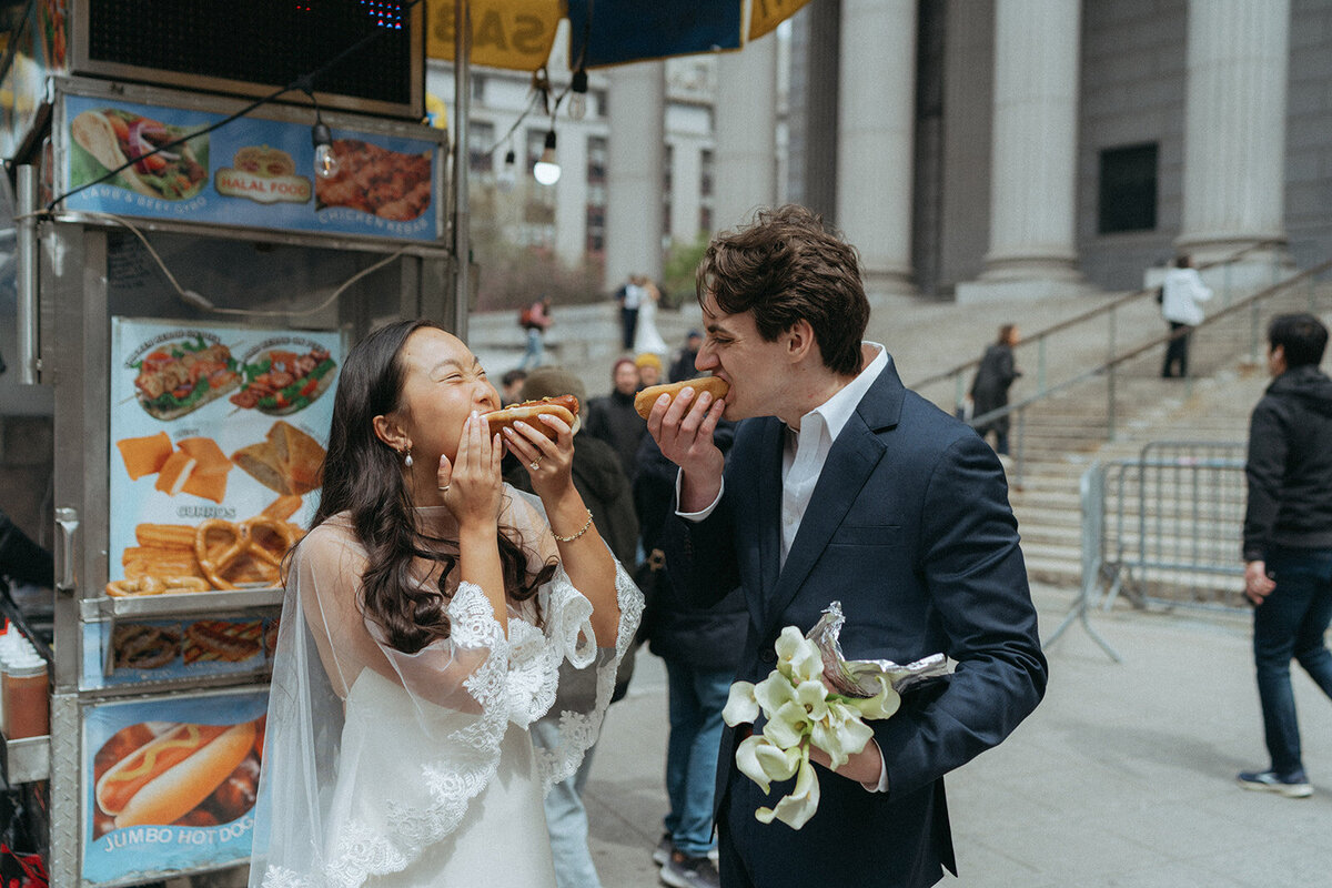 couple eating hot dogs outside after NY City Hall elopement shot by Elsie Goodman Photography | NYC Elopement Packages