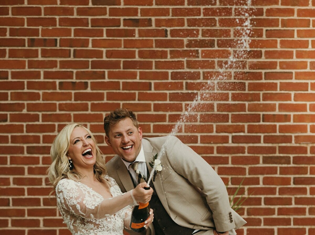 Wedding couple celebrating popping champagne bottle