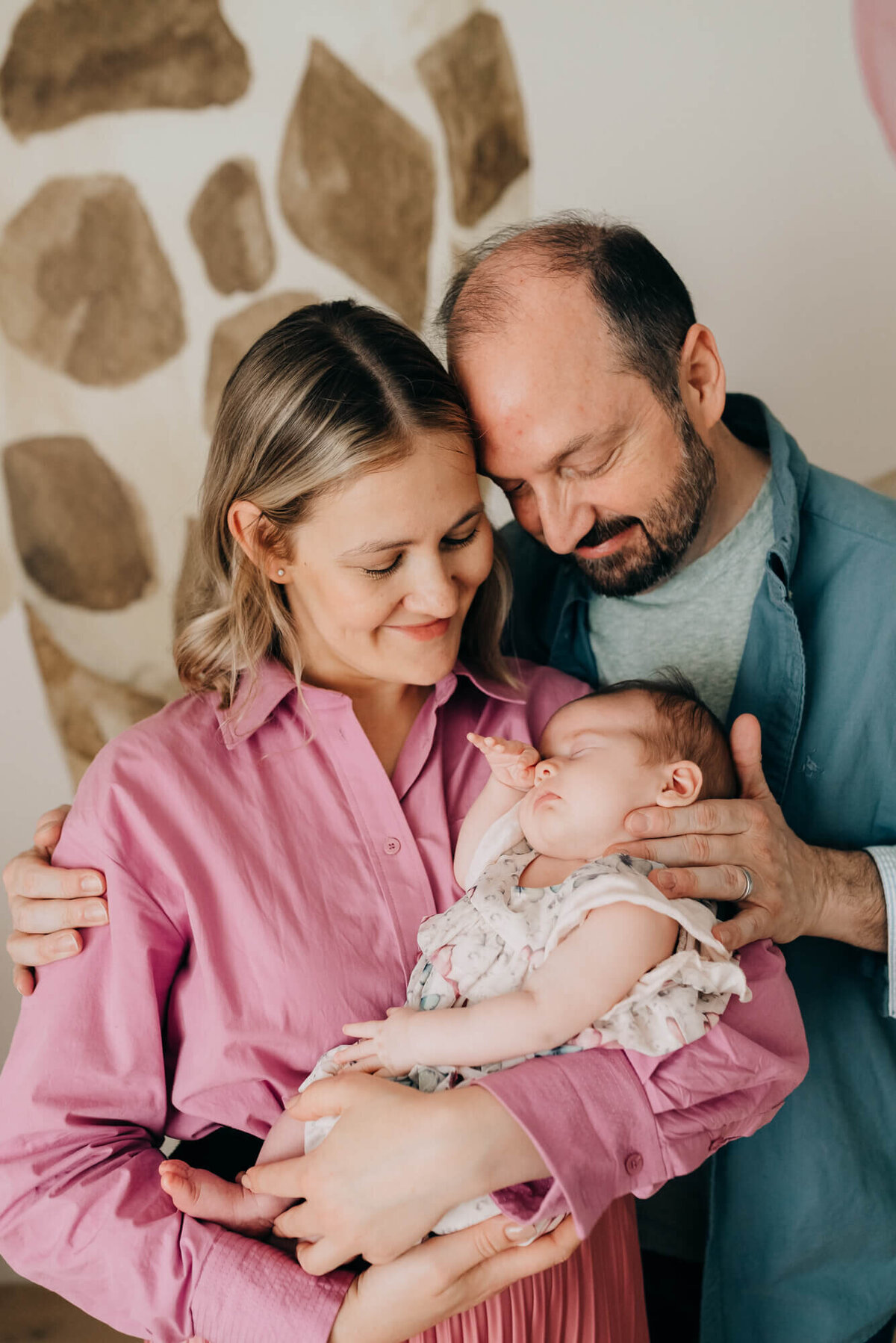 A mother and father hold their newborn daughter in her safari themed nursery