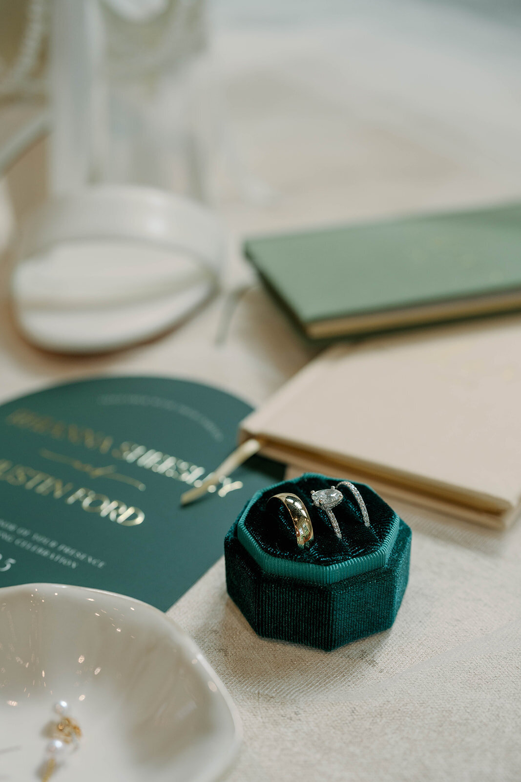 Flatlay detail shot featuring the wedding invitations, ring box, wedding rings, and delicate styling elements from a Leona Road wedding.