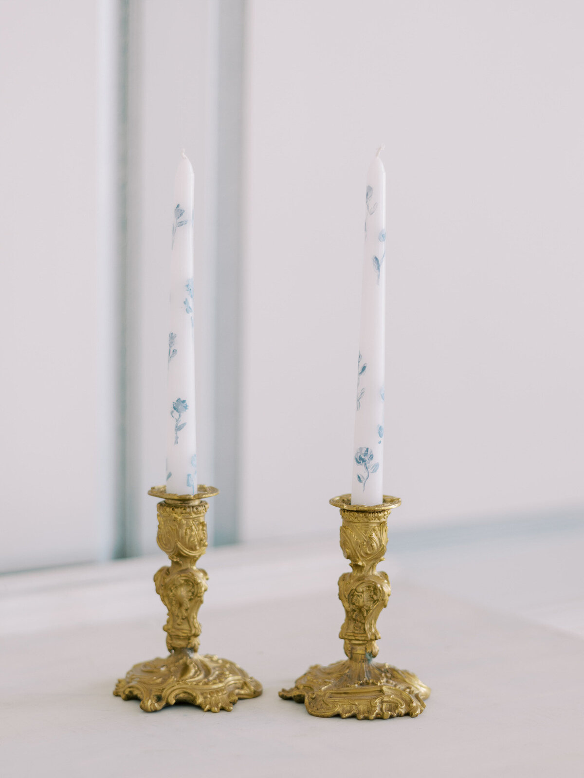 Elegant blue and white tapered candles in gold candleholders for Tuscan wedding
