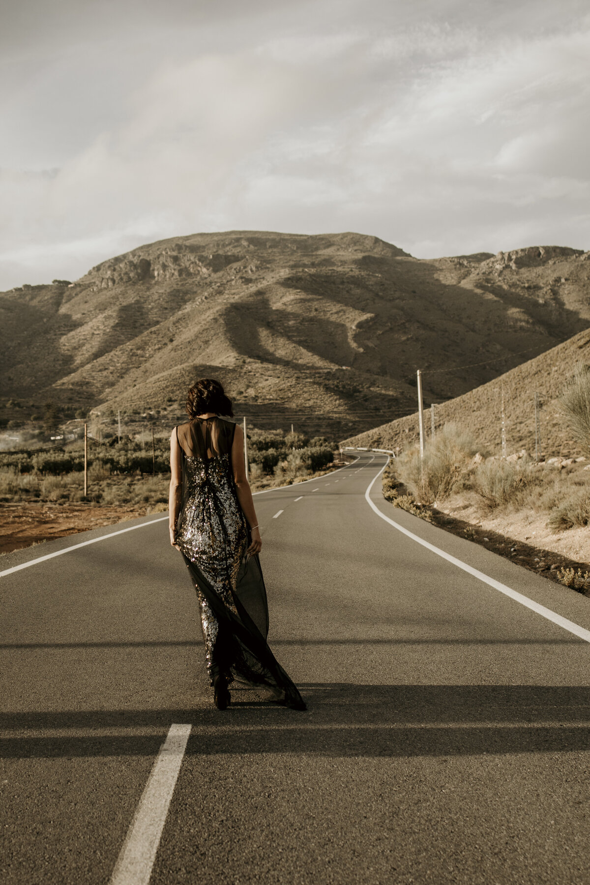 Model walking in the middle of a road with a beautiful designer dress on in Spain