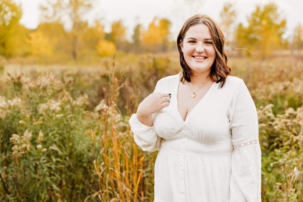 girl with short hair in a white long sleeve dress laughing during her senior session