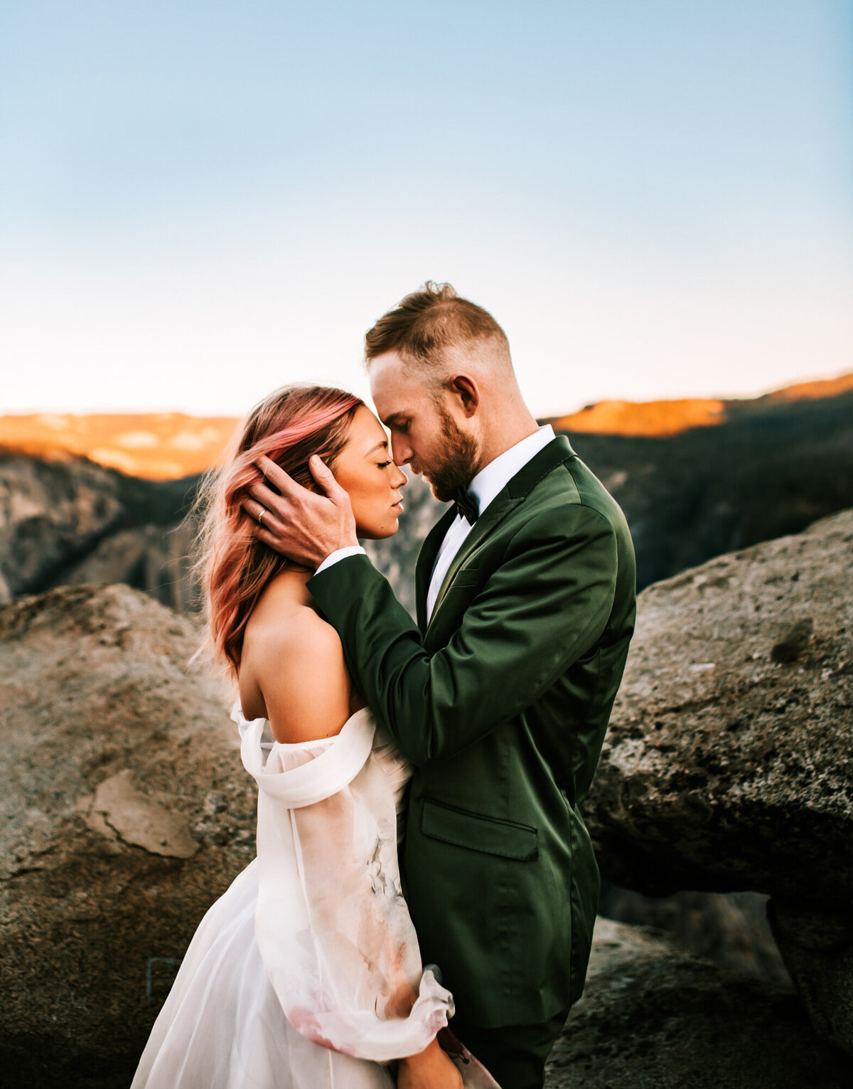 Couples Photography, a groom in a suit and a woman in her wedding dress draw close, face to face on the mountain top