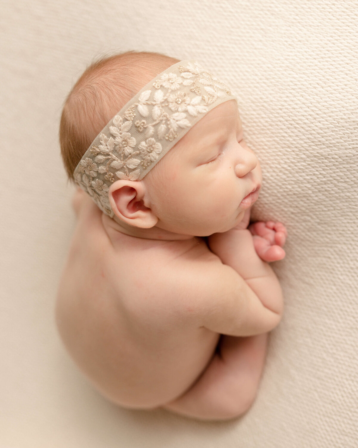 baby girl with embroidered headband sleeping with feet under arms