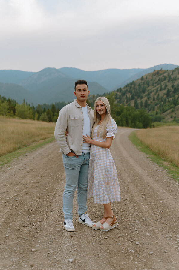 A more posed couples portrait of a man and woman. She has her hand on his stomach and he has his hand in the pocket of his jeans.