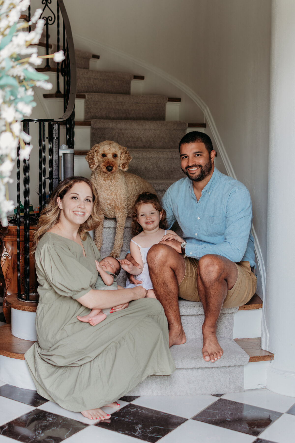 Family on the stairs in front of their home with their dog joining them during a newborn photo session in Chicago, IL