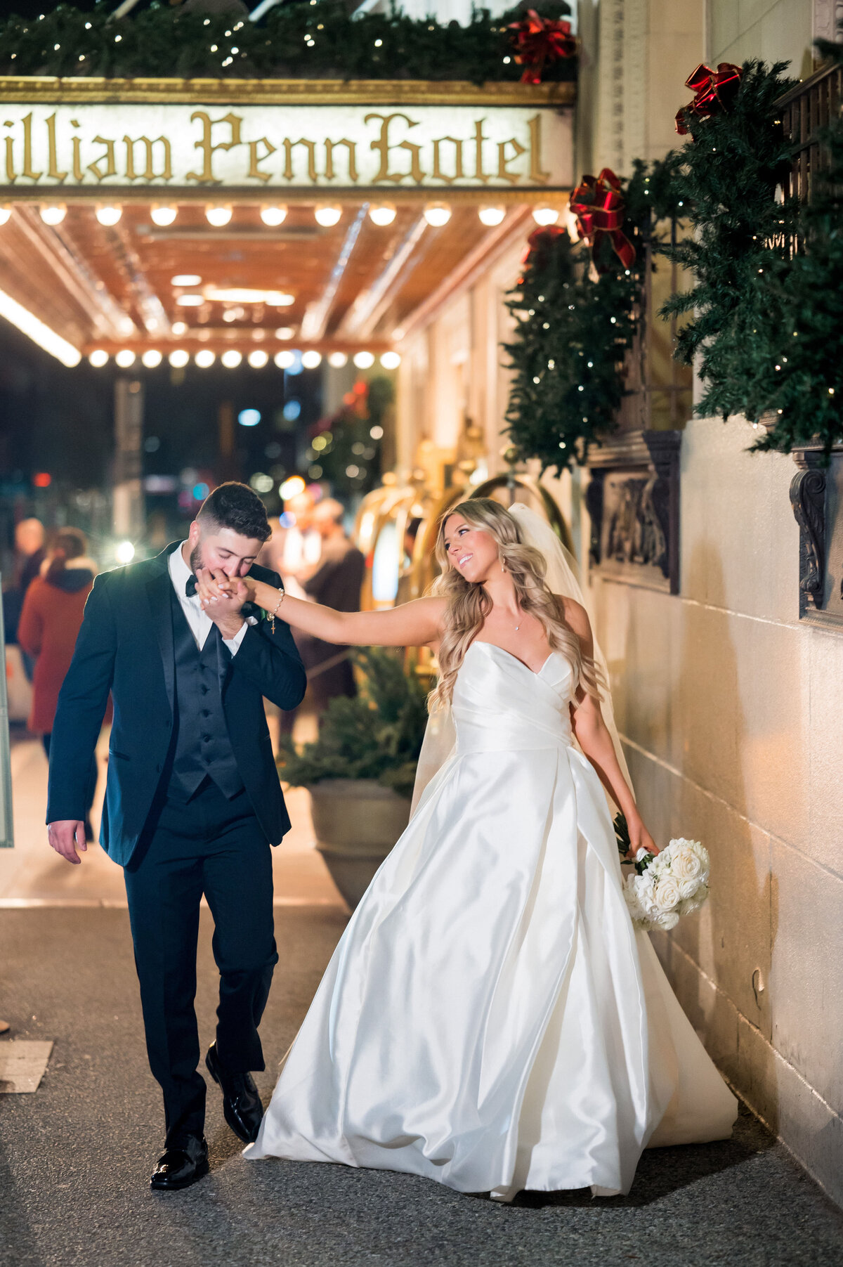 groom kissing bride hand as they walk down william penn place pittsburgh