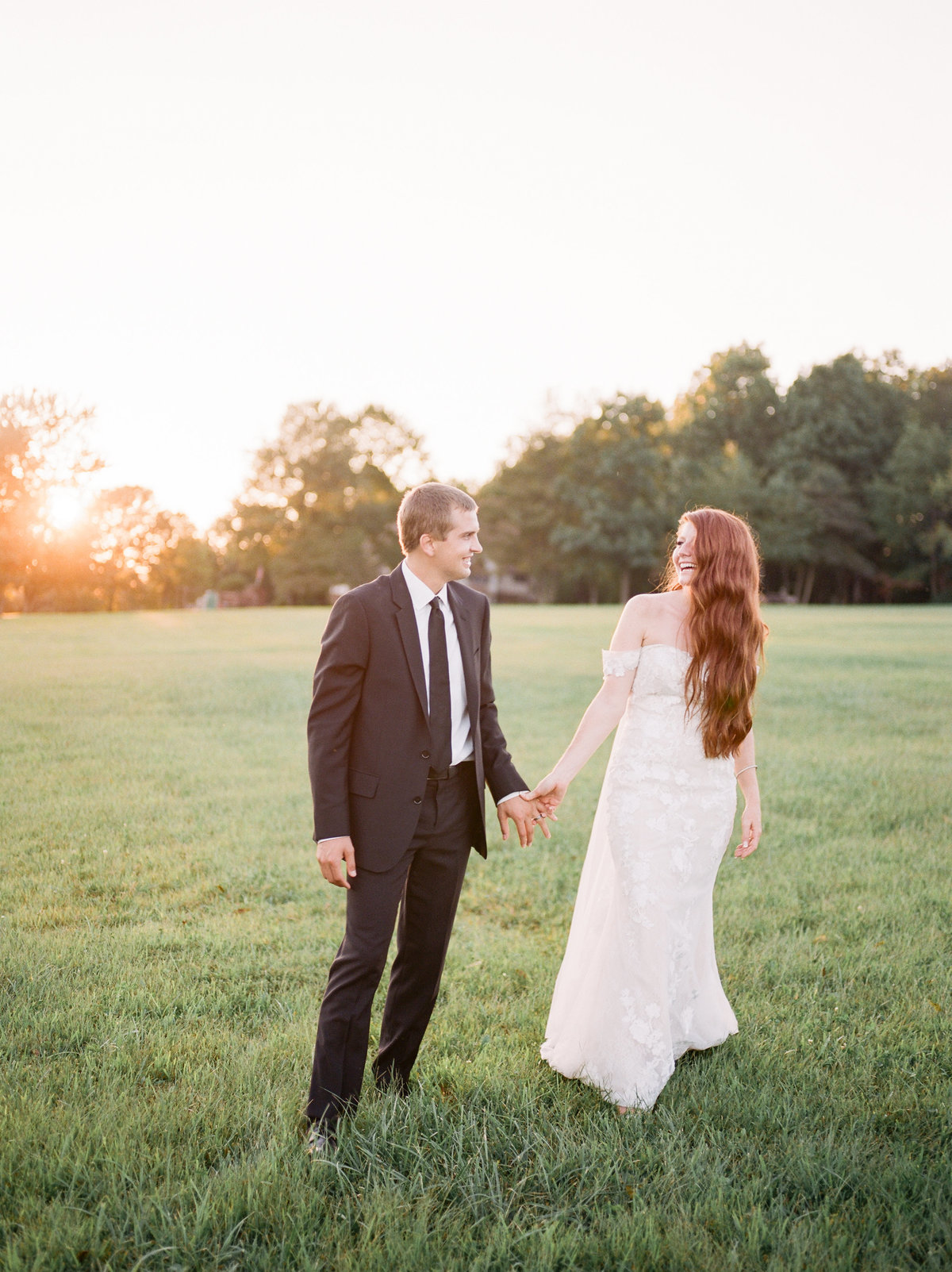 couple holding hands and walking in grass